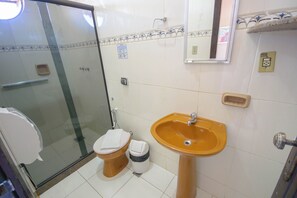 A bathroom with a glass shower enclosure, a toilet, a sink, and a mirror. - Buzios Centro Hotel by Kastel (Búzios)