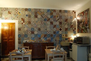 Una cucina con zoccolo in piastrelle, mobili impiallacciati in legno, un tavolo da pranzo con sedie e un forno a microonde su un piano di lavoro.