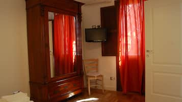 Une pièce avec une armoire en bois, un téléviseur fixé au mur, une chaise et une porte.