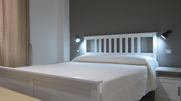 Un letto rifatto con una testiera bianca e due lampade sui comodini.