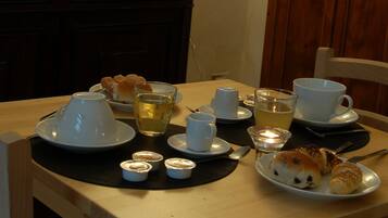 A dining table set with plates, cups, and a candle, in a room with wooden furniture and a cabinet.