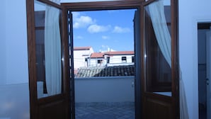 An open door leading to a balcony with a tiled floor and a view of buildings in the distance. - B&B Federico Secondo (Palermo)