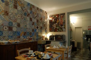 Una cucina con rivestimento piastrellato, un tavolo da pranzo apparecchiato per due persone e un frigorifero sullo sfondo.