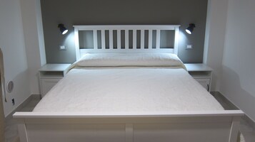 Un letto rifatto con un poggiatesta bianco e due abat-jour.