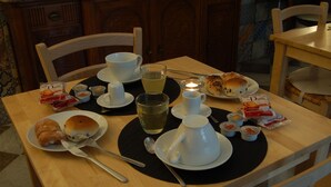 A breakfast table with a cup, teapot, teacup, teacandle, plate with pastries, and condiments. - B&B Federico Secondo (Palermo)