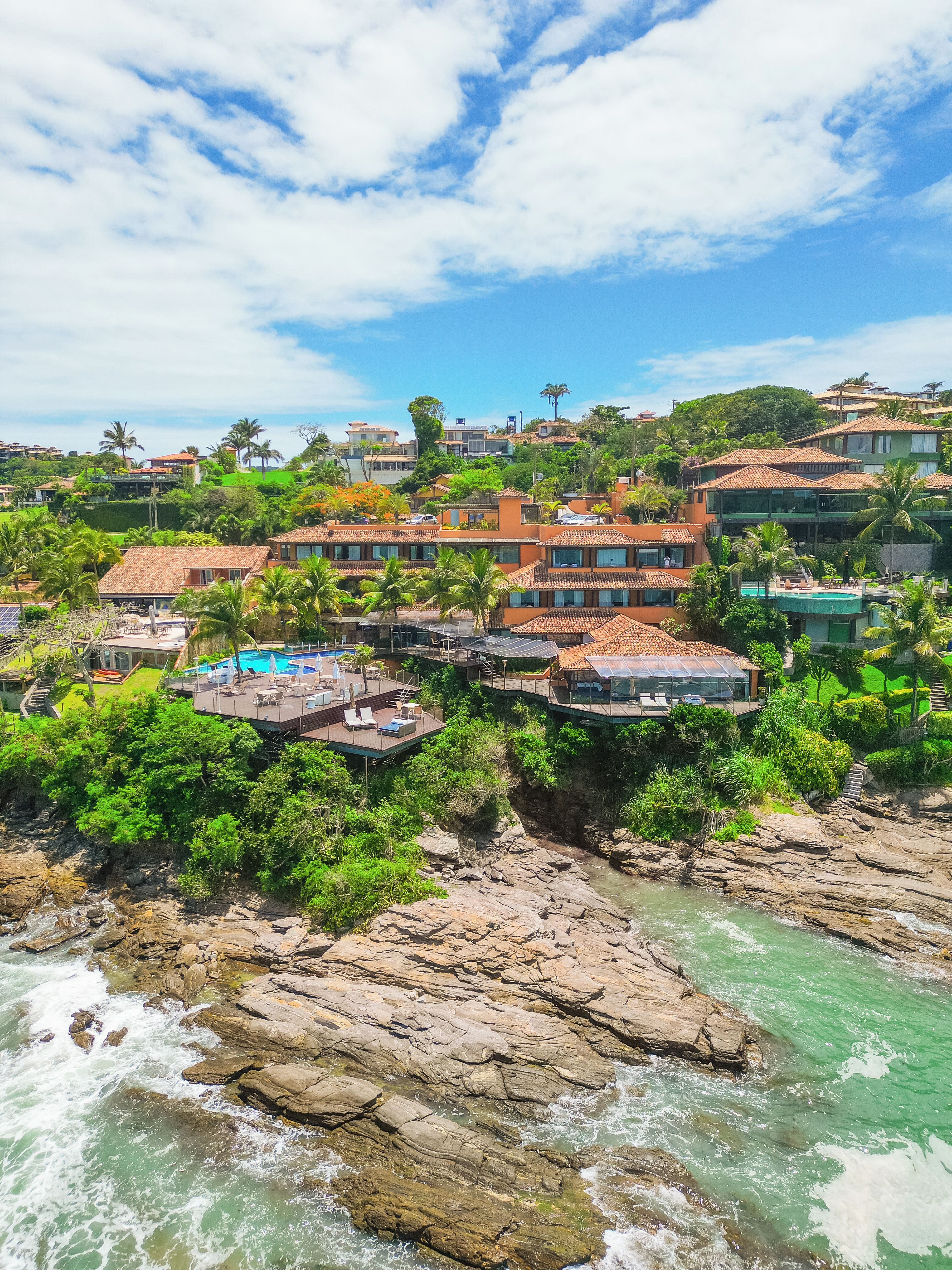 A coastal property with multiple buildings, a swimming pool, and a rocky shoreline.