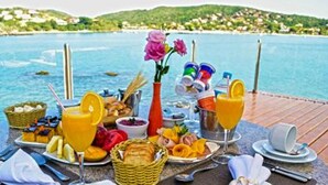 A breakfast setup with a view of a body of water and hills in the background. - Hotel Ferradura Private (Búzios)