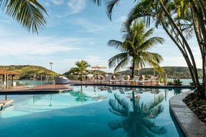 Una piscina al aire libre, sombrillas, sillones reclinables de piscina