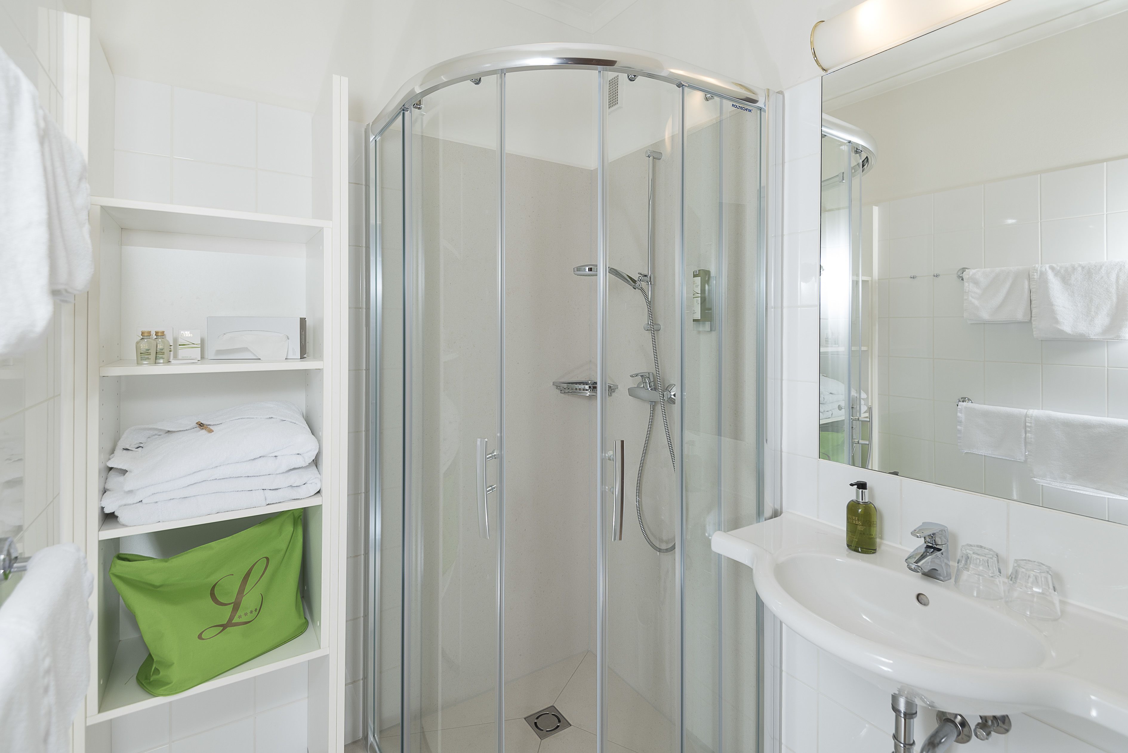 Une salle de bain moderne avec une douche à parois de verre, un lavabo blanc et un miroir.