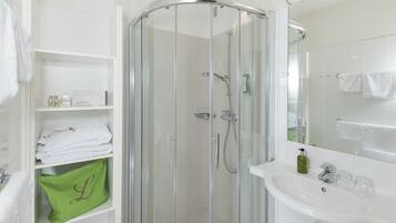 Une salle de bain moderne avec une douche à parois de verre, un lavabo blanc et un miroir.