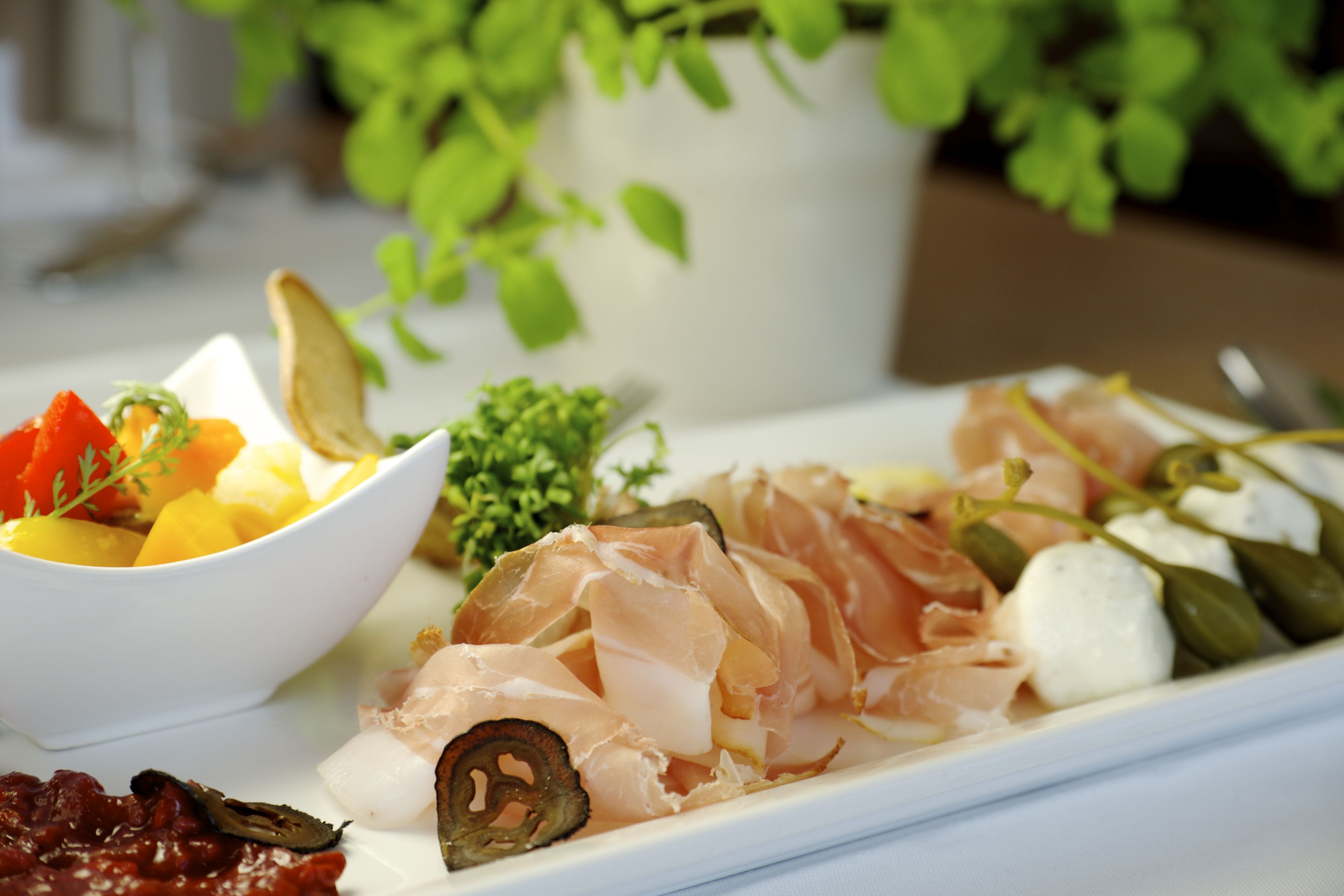 Una tabla de embutidos con diversos quesos, carnes y verduras.