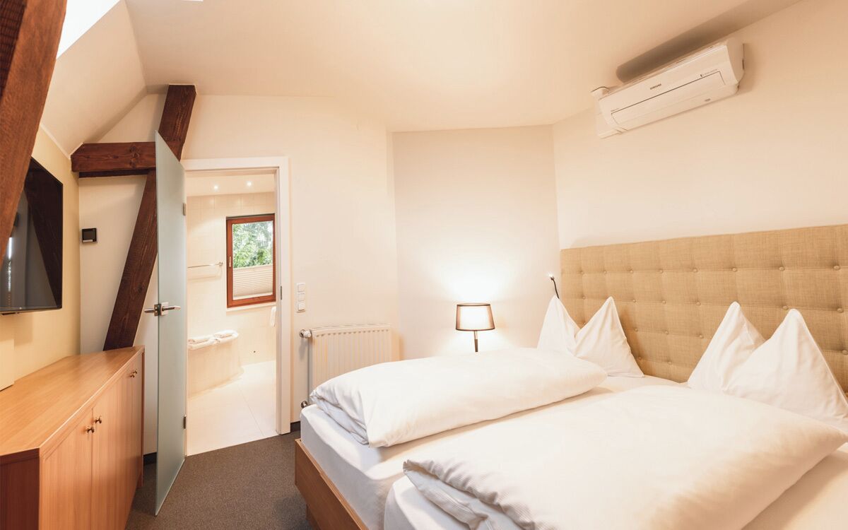 Ein Schlafzimmer mit einem Bett, einer Nachttischlampe, einer Heizung und einem Fernseher an der Wand.