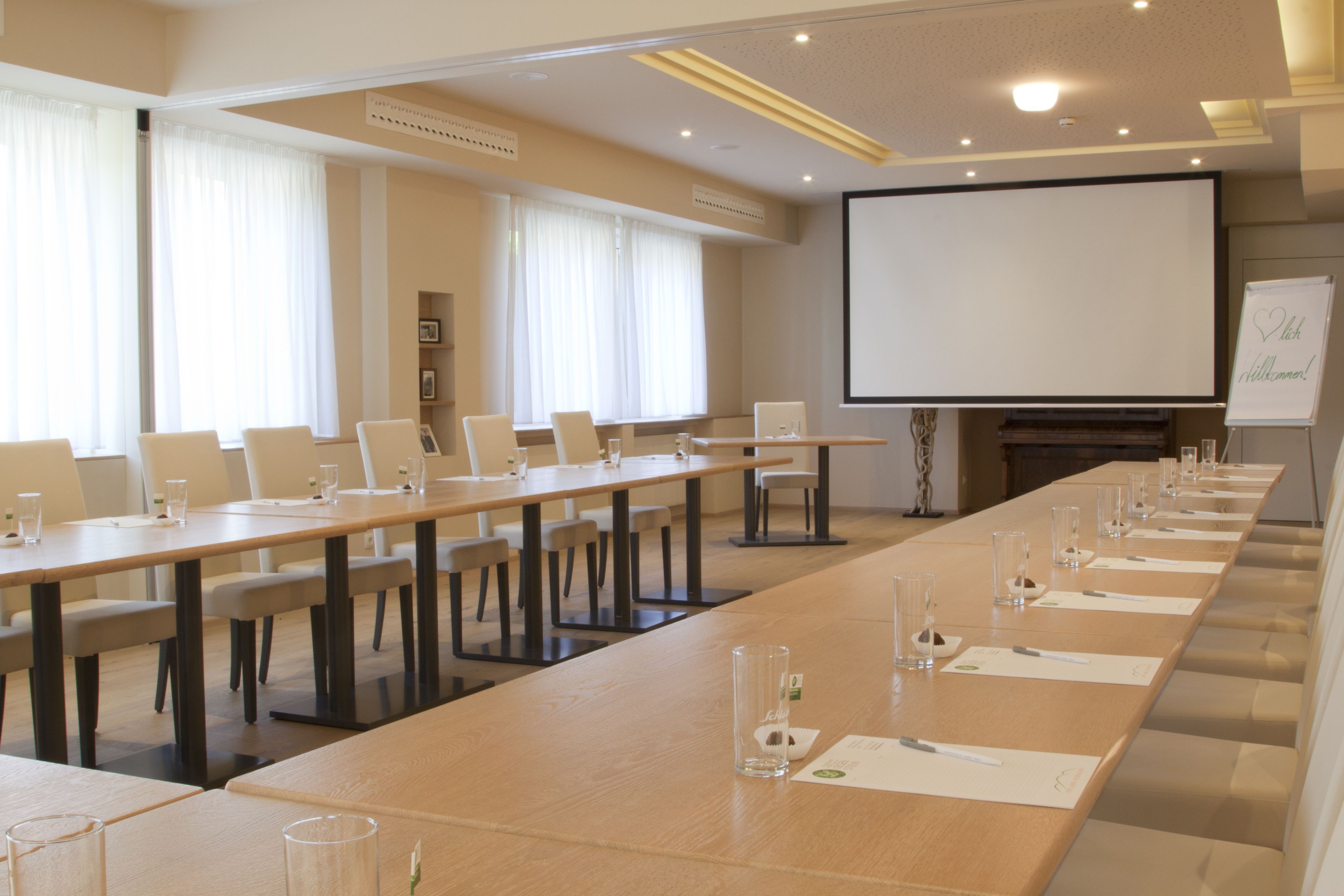 Un salón de conferencias con una mesa larga, sillas y una pantalla para proyector.