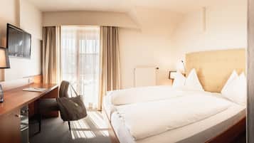 Habitación de hotel con cama, escritorio, silla y televisor en la pared.