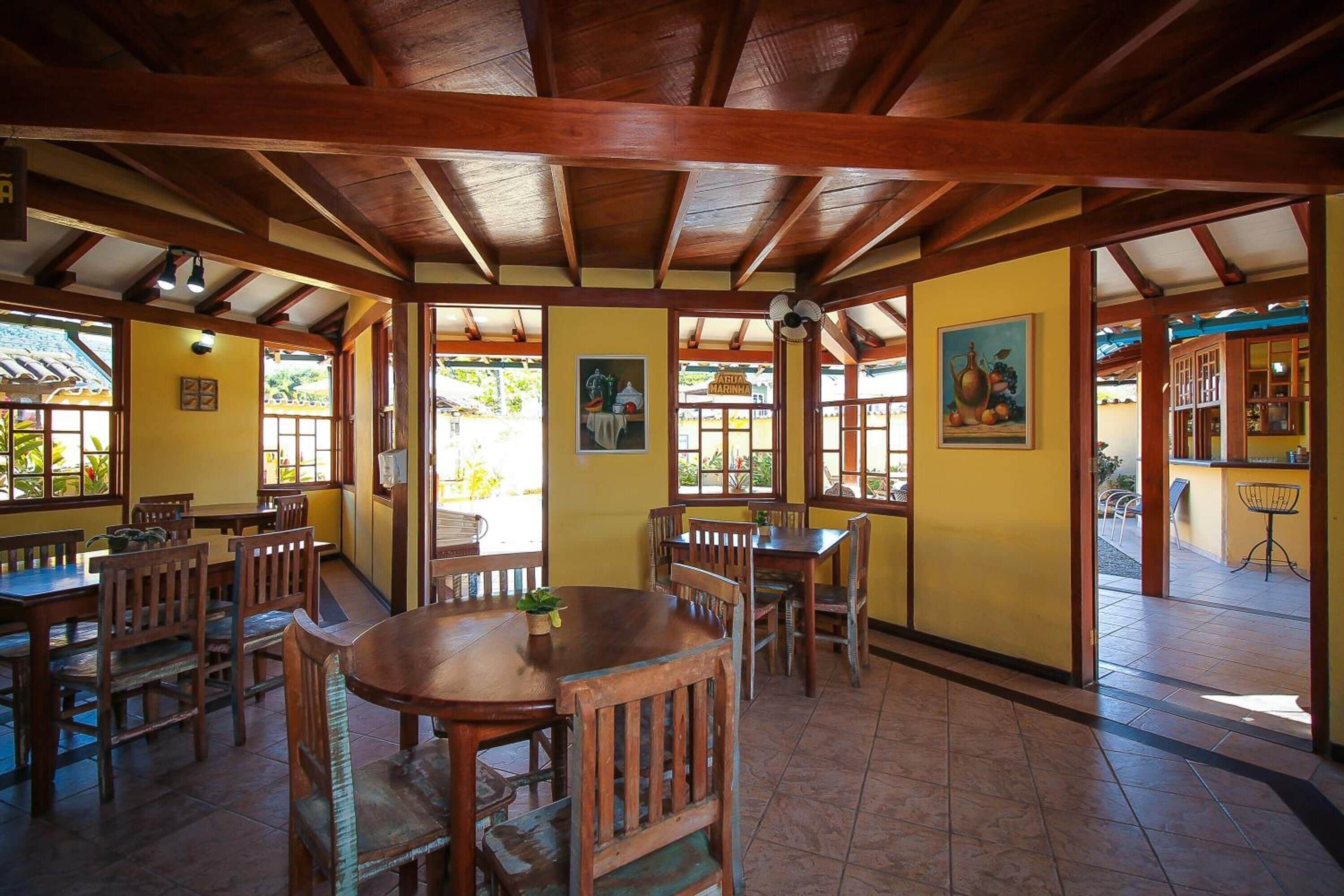 A restaurant with wooden tables and chairs, yellow walls, and a tiled floor.