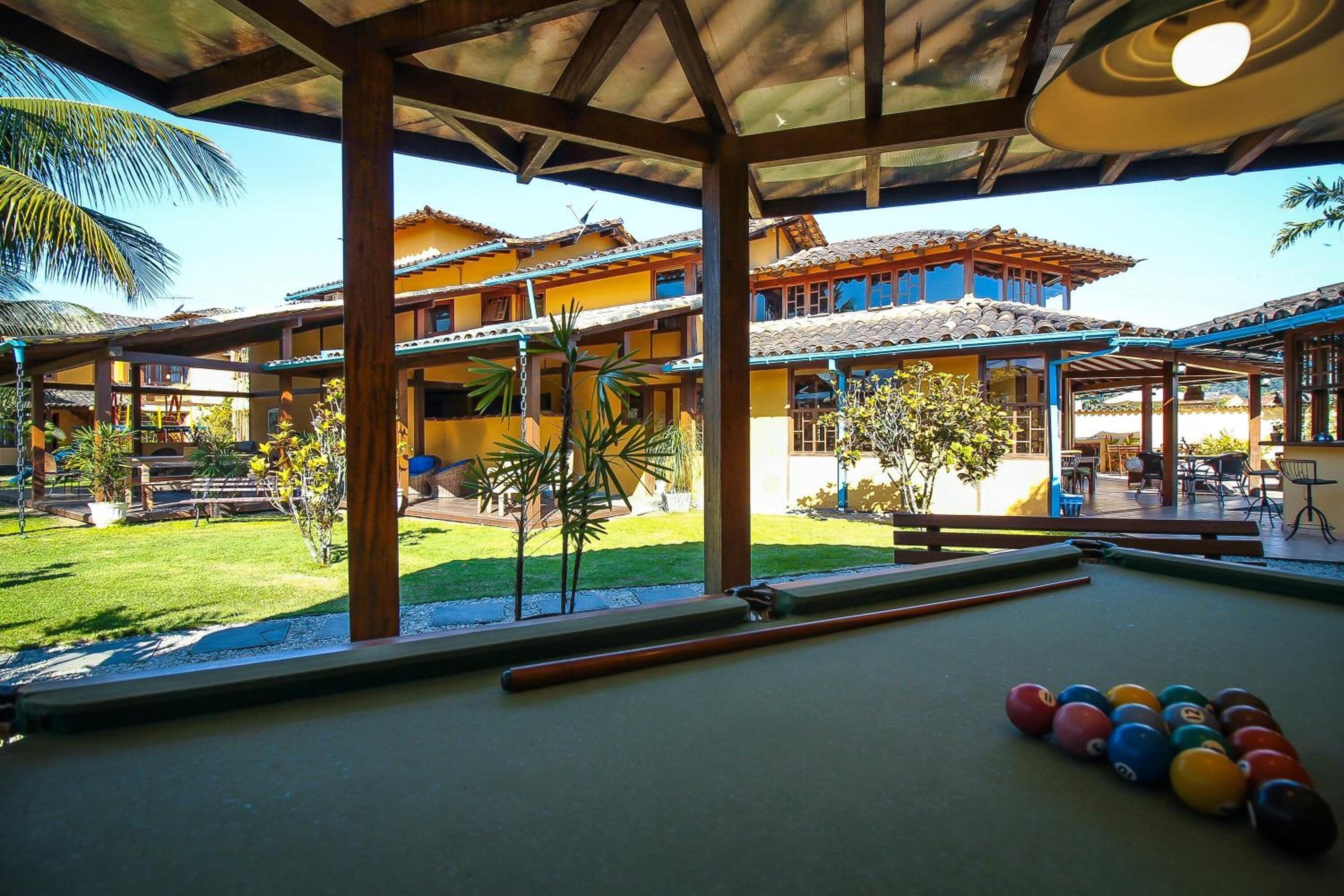 A pool table with billiard balls and a view of a building with a tiled roof and outdoor seating.
