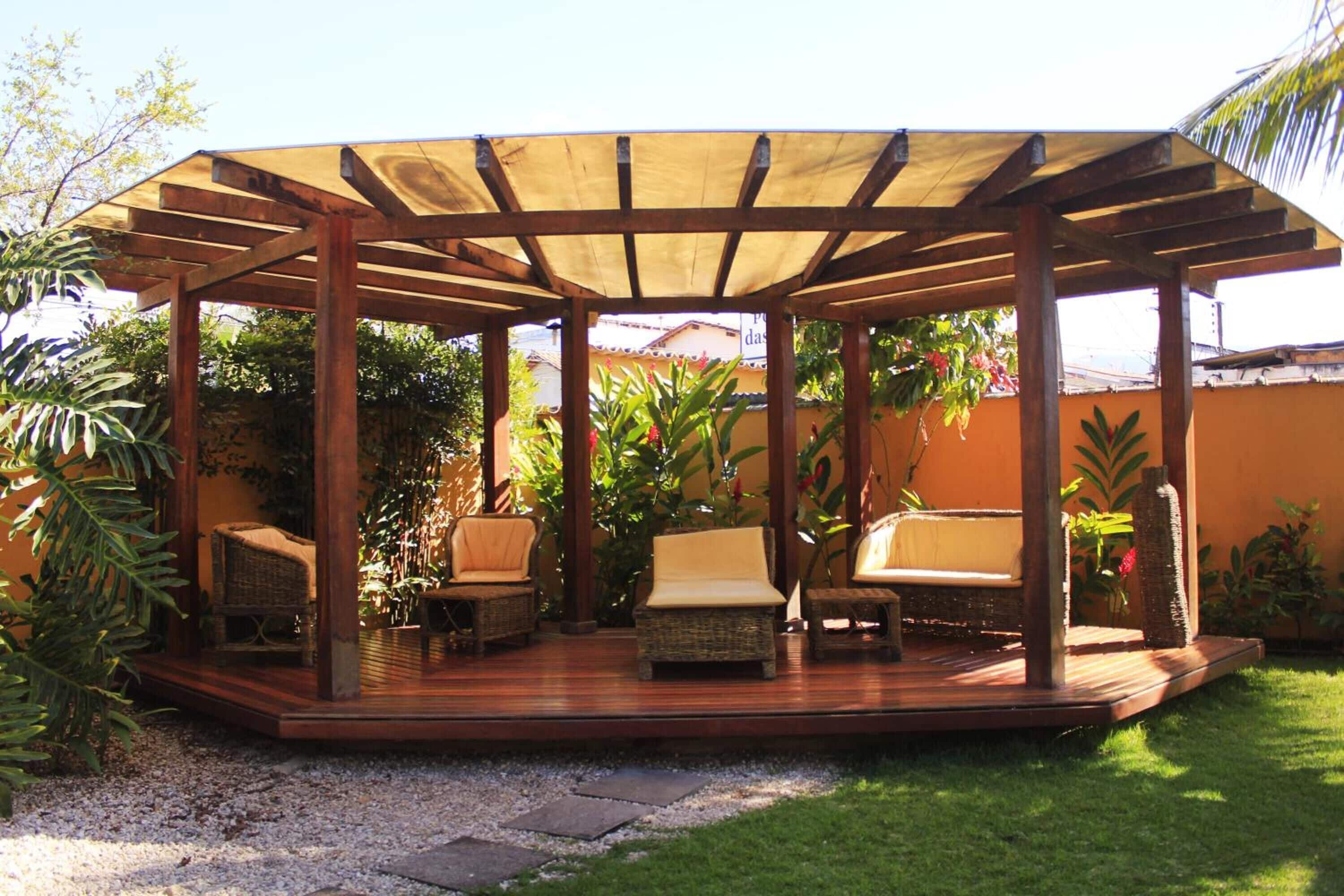 A covered outdoor seating area with wicker furniture and a wooden deck.