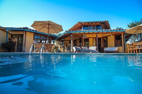 Una piscina al aire libre, sombrillas, sillones reclinables de piscina. Pousada das Pedras