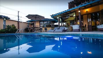 Una piscina al aire libre, sombrillas, sillones reclinables de piscina