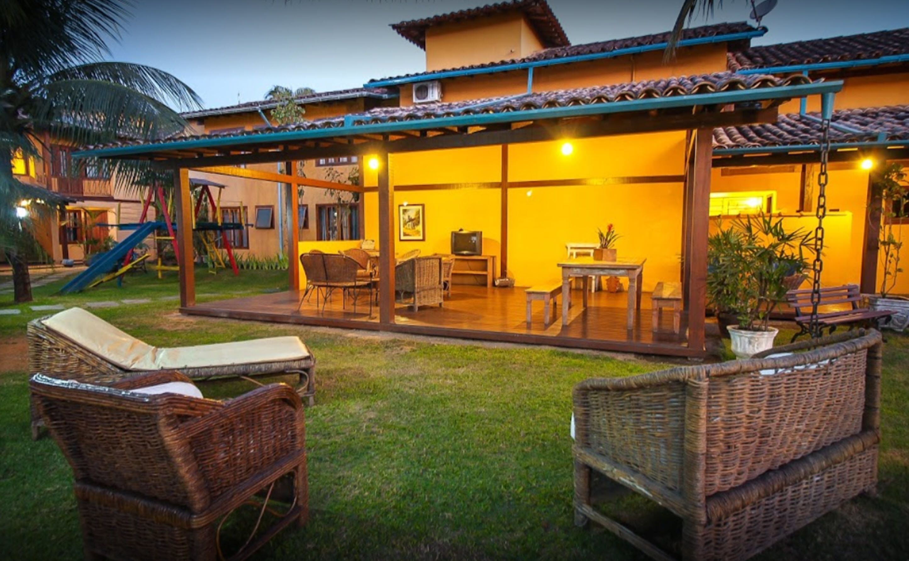 A covered outdoor patio with wicker furniture, a slide, and a television.