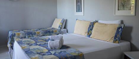 Una habitación de hotel con dos camas, cada una con ropa de cama estampada con motivos florales y almohadas a juego. Hay un cuadro en la pared y una mesita de noche junto a la cama.