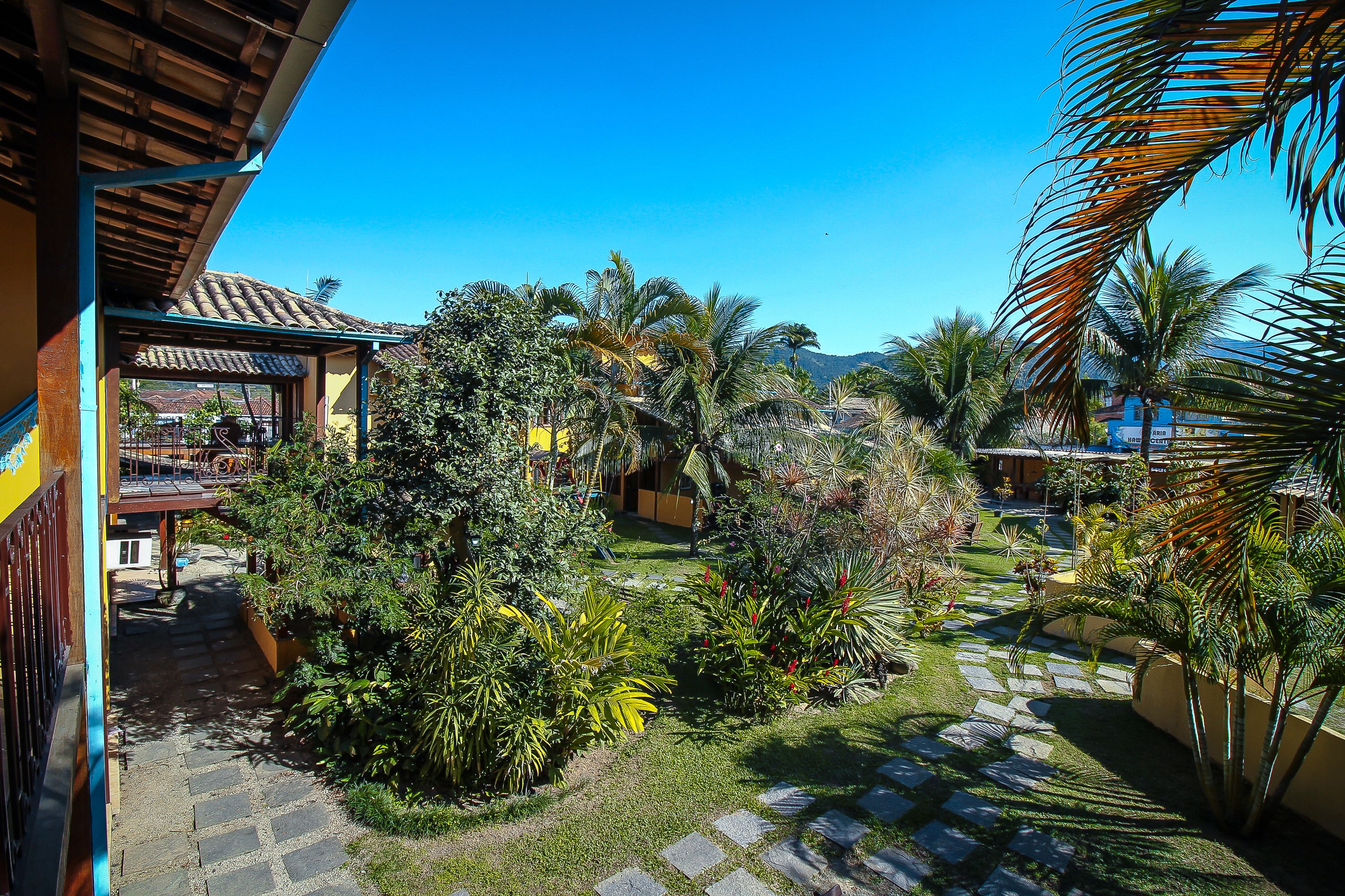 A courtyard with palm trees, a stone pathway, and a building with a tiled roof.