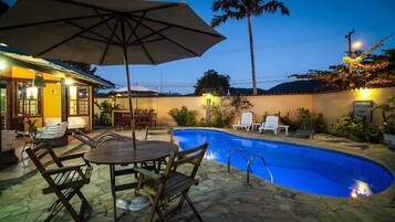 Una piscina al aire libre, sombrillas, sillones reclinables de piscina