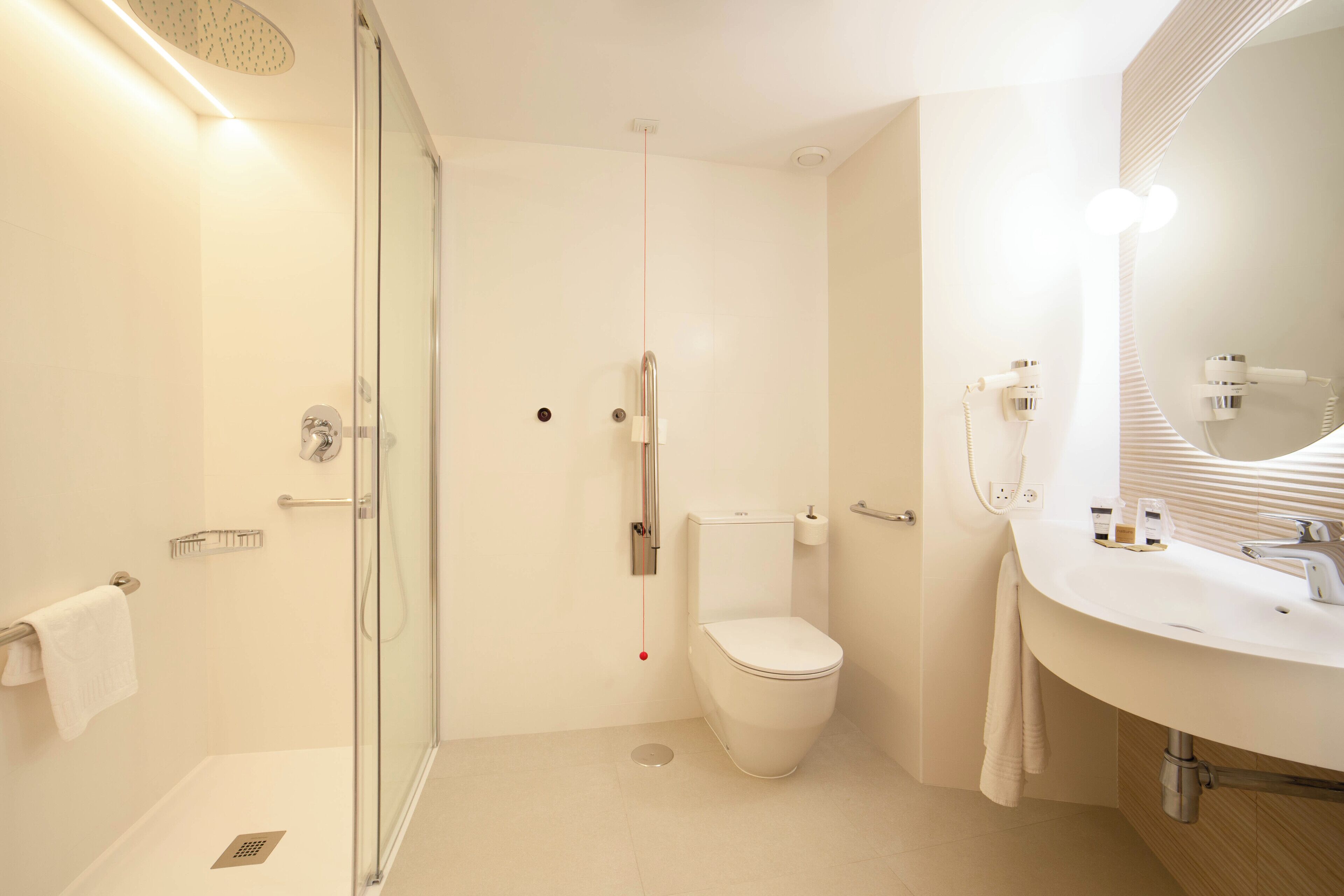Een moderne badkamer met een douchecabine van glas, een wit toilet en een wastafel met spiegel.