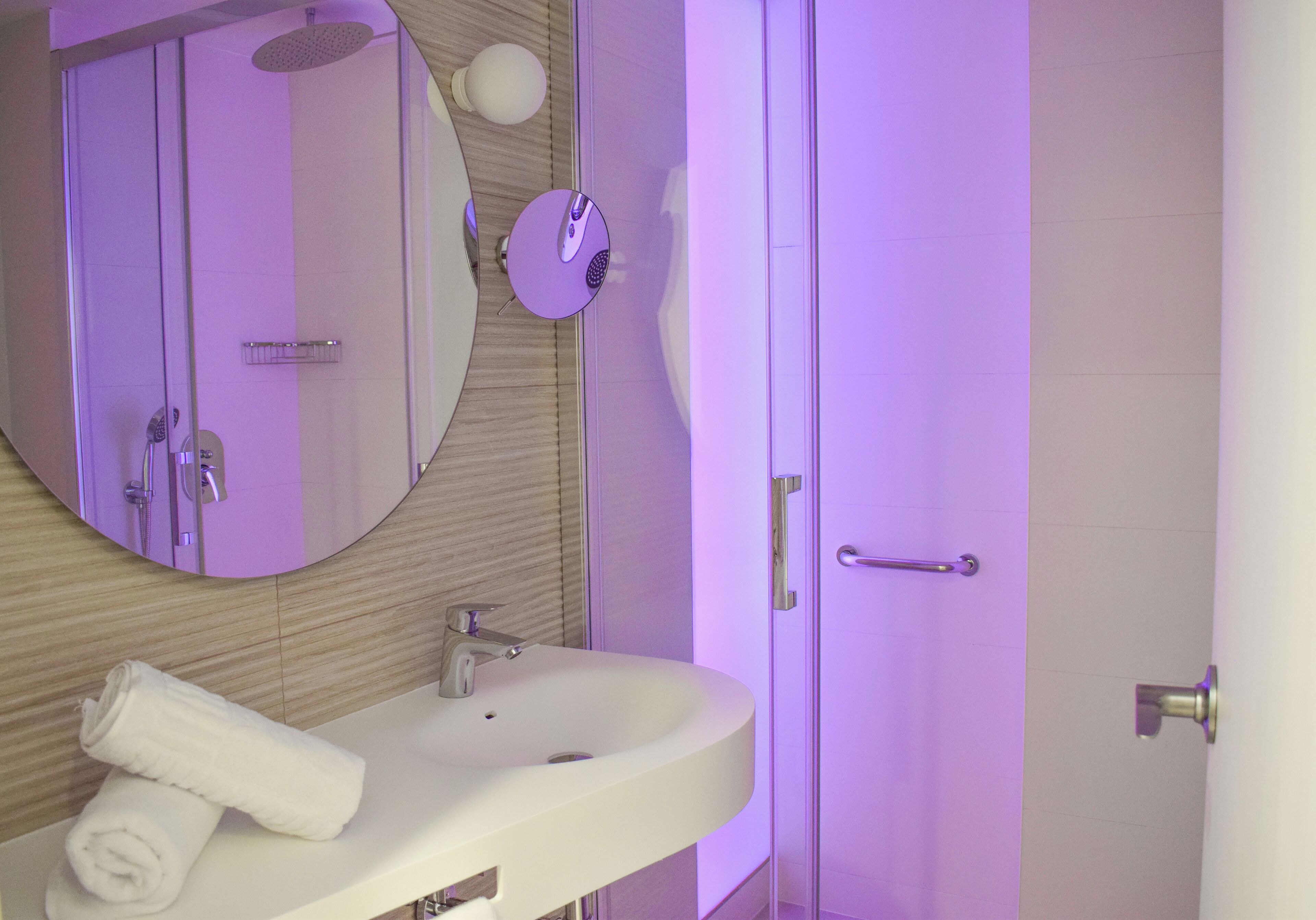 Un baño con un lavamanos blanco, un espejo y una ducha.