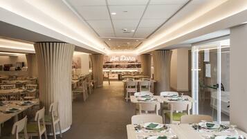 Un restaurante moderno con mesas y sillas ordenadas, un letrero central que dice 'Hot Dishes' y una decoración interior limpia y contemporánea.