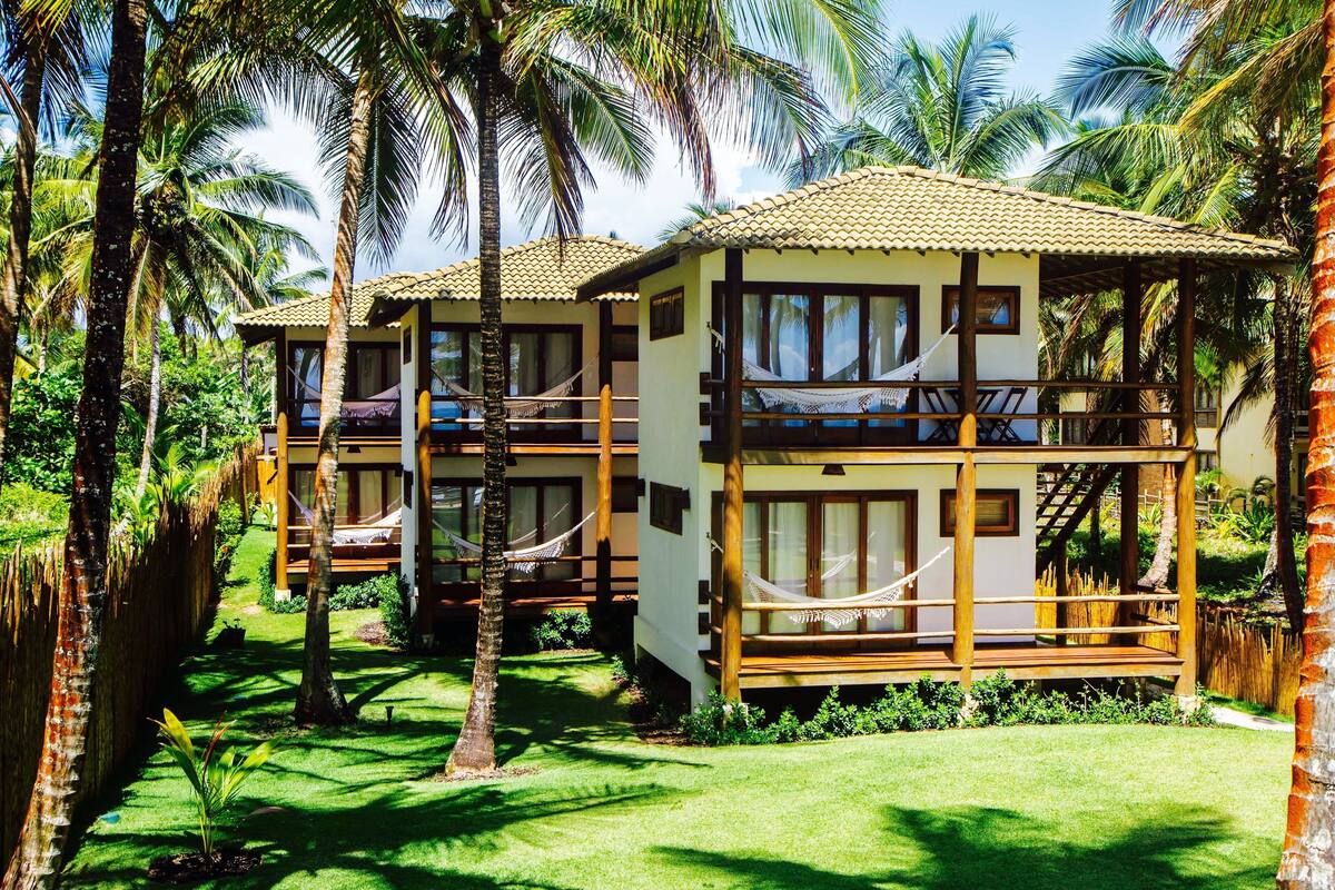 A resort with two-story buildings, each with a balcony and a hammock.