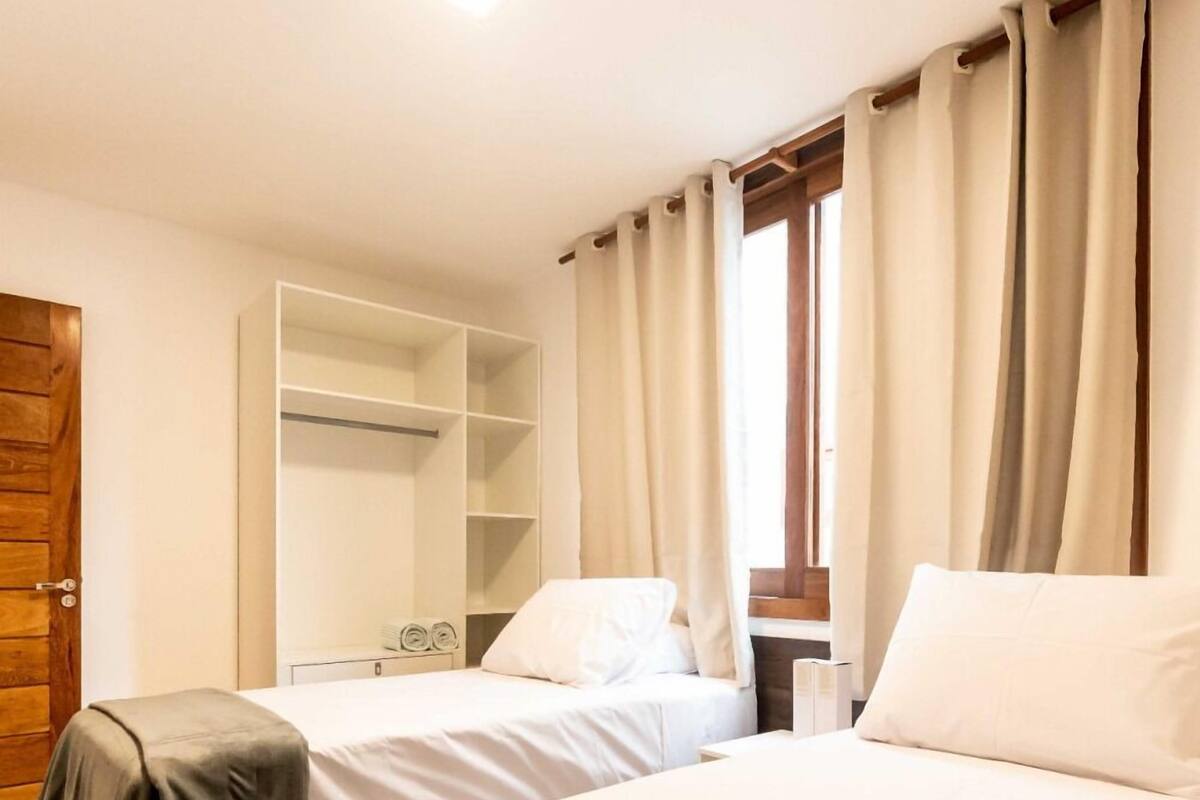 A hotel room with two beds, a wardrobe, and a window with curtains.