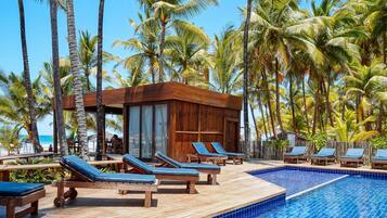 Un espace aménagé au bord de la piscine, avec des chaises longues en bois et une piscine.