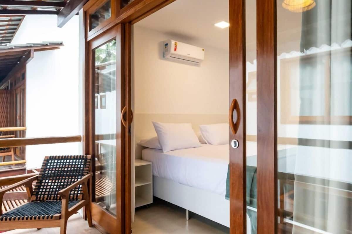 A wooden-framed room with a bed, a chair, and an air conditioning unit.