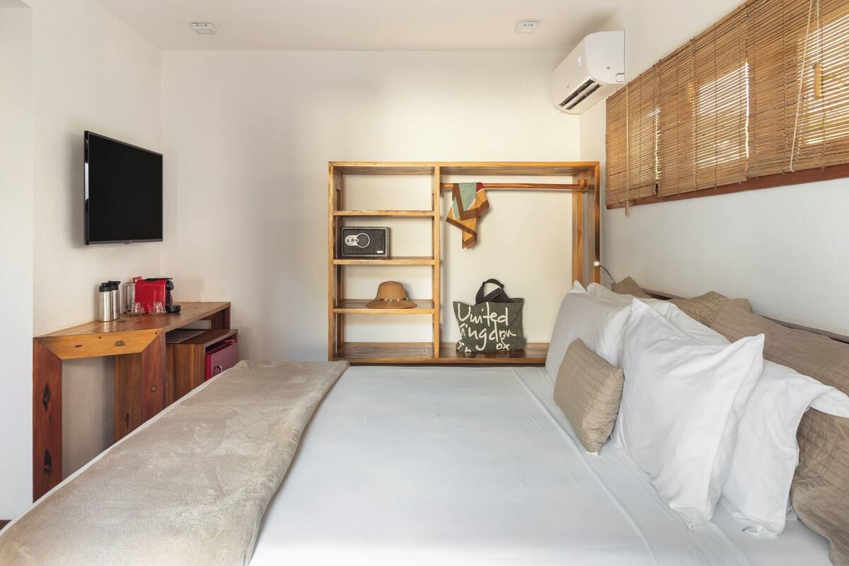 A bedroom with a bed, a desk, a wardrobe, and a television.
