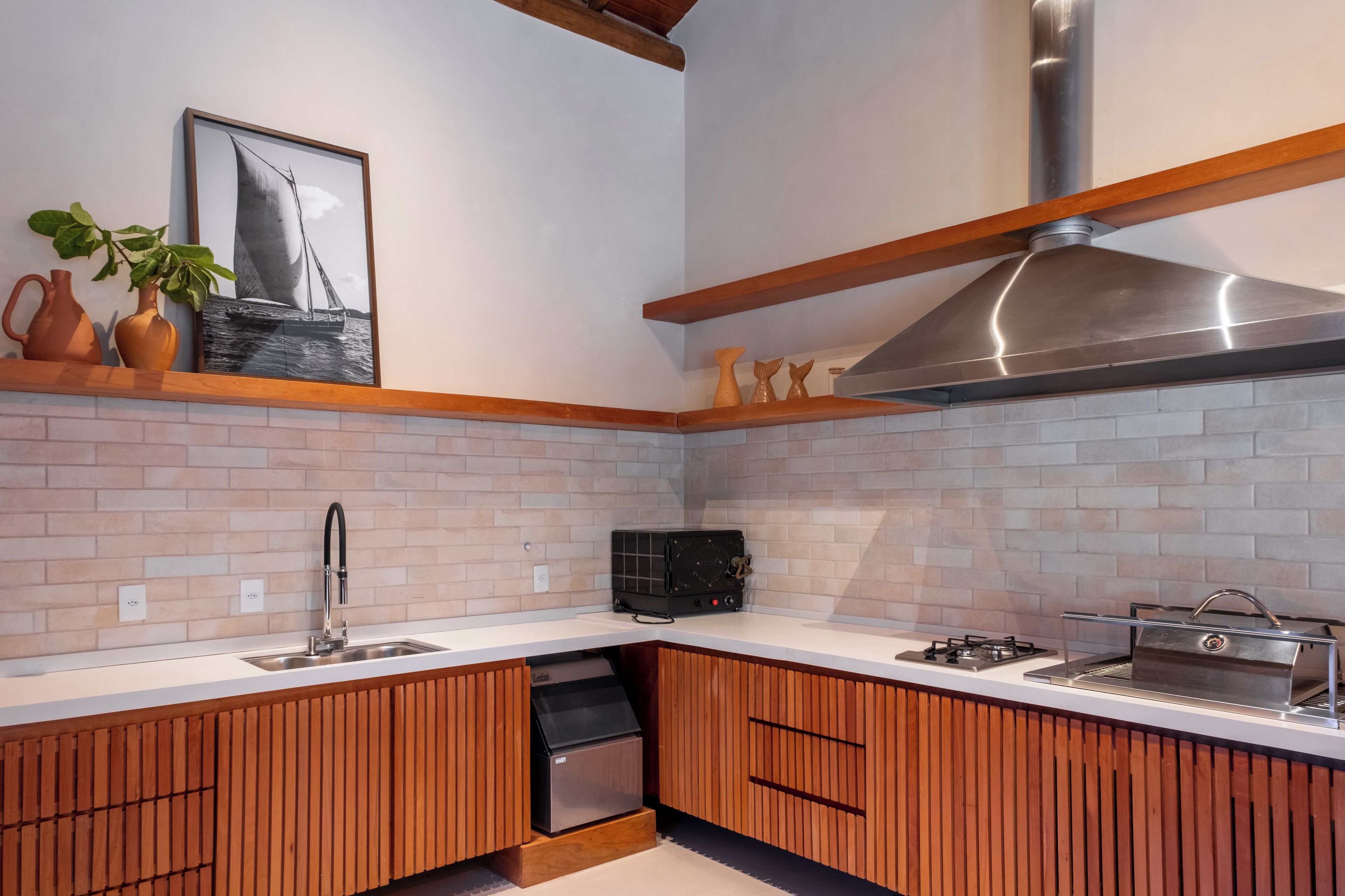 Una cocina moderna con salpicadero de ladrillo, armarios de madera, campana extractora de acero inoxidable y lavavajillas integrado.