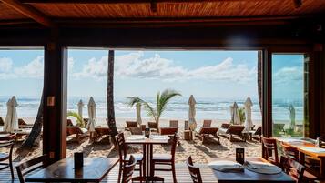 A beachside restaurant with outdoor seating overlooking the ocean.