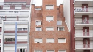 Un hôtel à plusieurs étages, doté d’une façade en briques, de balcons et d’une entrée centrale.