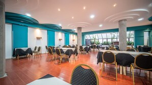 Un vaste espace de restauration intérieur, doté de nombreuses tables et chaises, de grandes fenêtres et d’un design de plafond moderne.