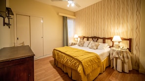 Quarto de hotel com cama, mesas de cabeceira, escrivaninha e guarda-roupa.