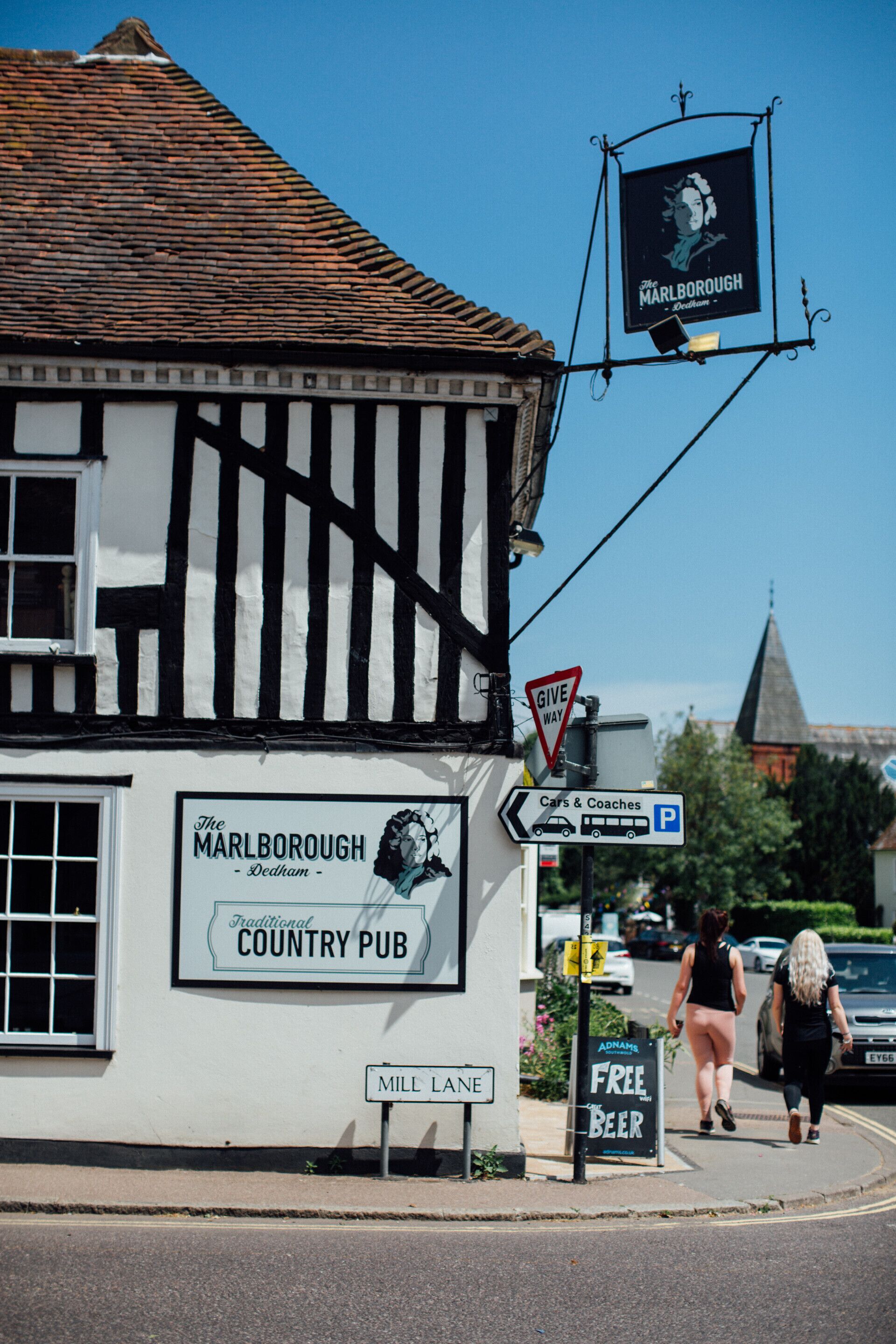 A traditional country pub with a sign advertising free beer and a 'Give Way' traffic sign.