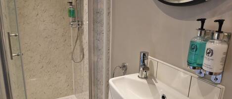 A bathroom with a glass-enclosed shower, a white sink, and patterned floor tiles.