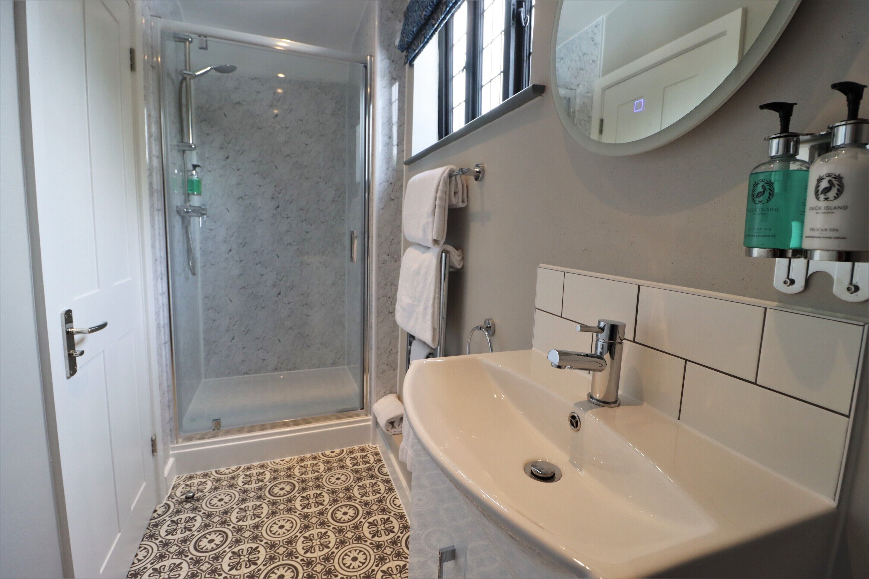 A bathroom with a shower, a sink, and a mirror.
