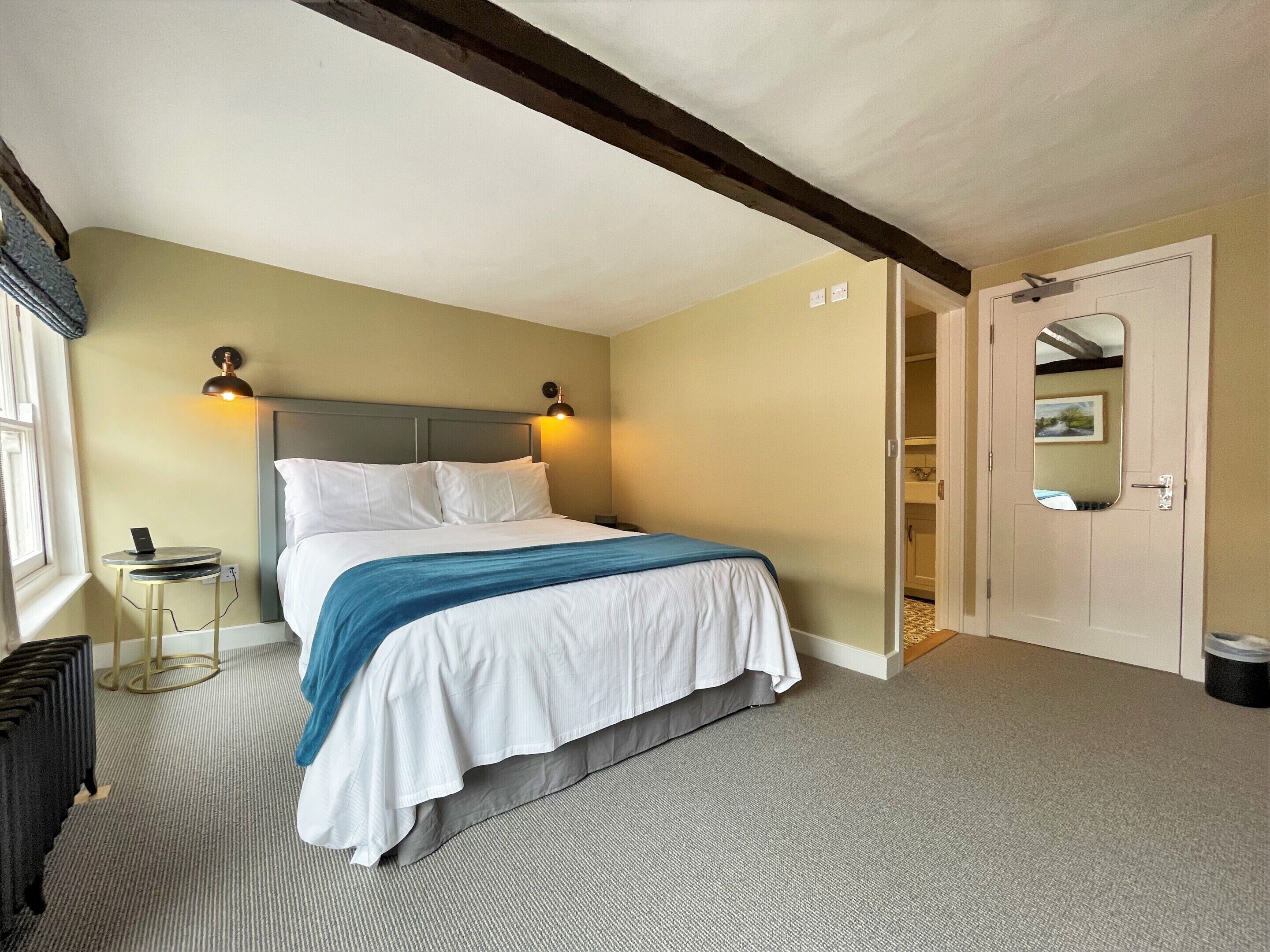 A neatly arranged bedroom with a bed, bedside tables, and a door leading to a bathroom.