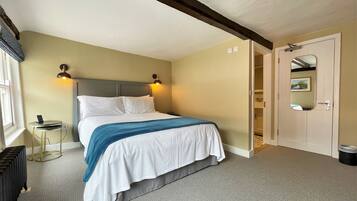 A neatly arranged bedroom with a bed, bedside tables, and a door leading to a bathroom.