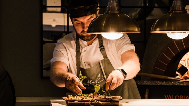 Een kok bereidt eten in een keuken met twee industriële ovens.