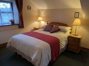 A neatly made bed with a red blanket, two bedside lamps, and a wooden nightstand. - Middle Flass Lodge (Clitheroe)