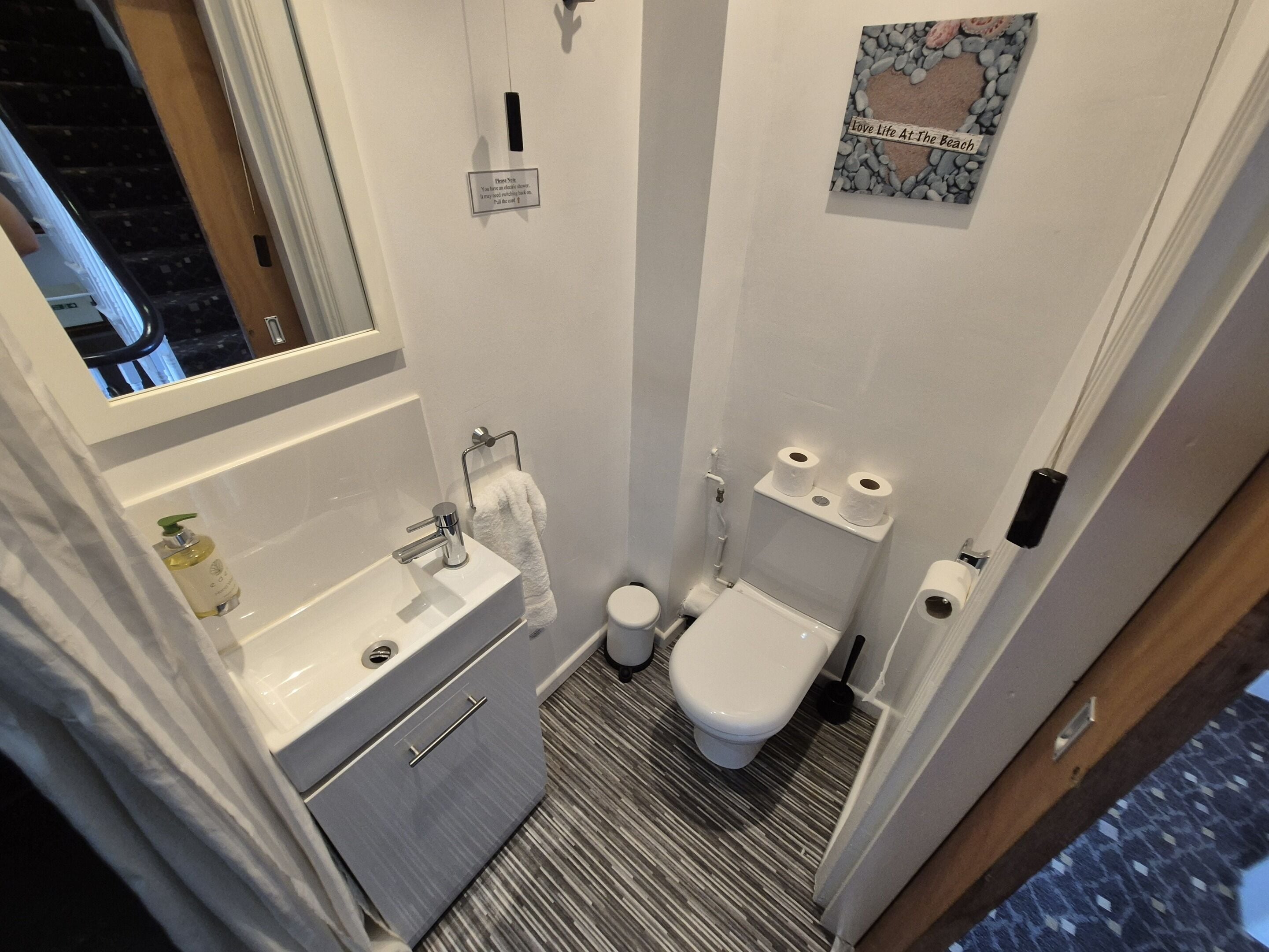 Un bagno piccolo e funzionale, con lavandino, water e portasciugamani bianchi.