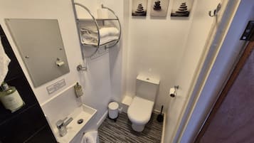 Une petite salle de bain comprenant des toilettes, un lavabo et un porte-serviettes.