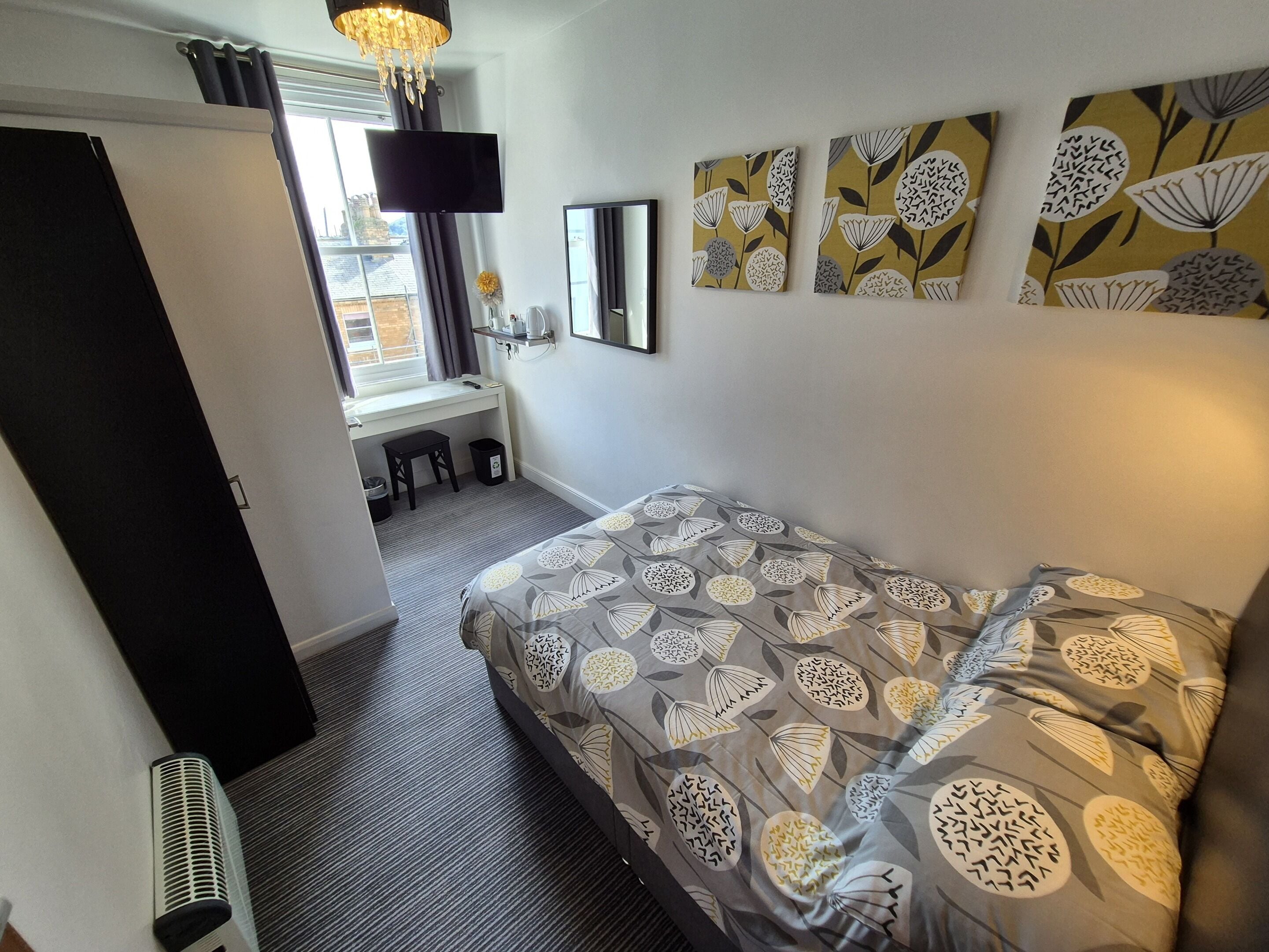 Quarto com cama, escrivaninha, cadeira e janela.
